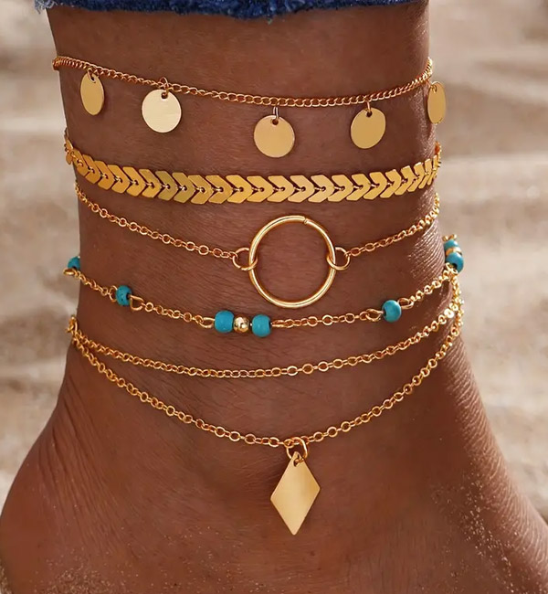 Layered gold anklets with turquoise beads, charms, and chain links
